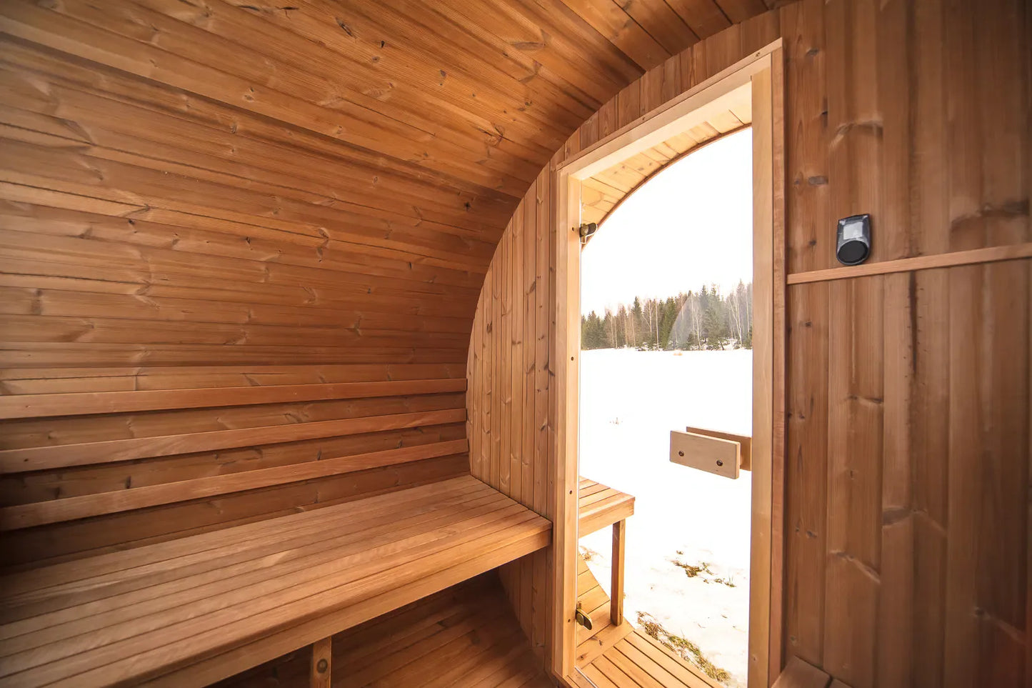 Interior bench seating inside the Hekla Barrel Sauna 210, view towards the door.