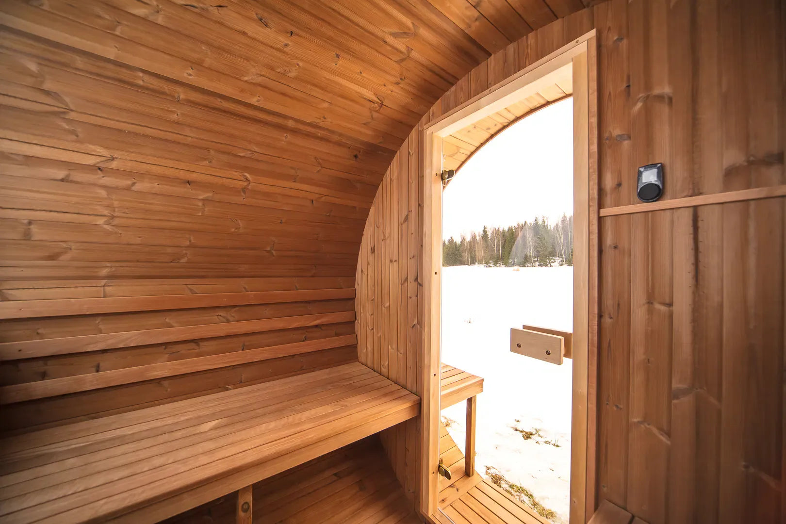 Interior bench seating inside the Hekla Barrel Sauna 210, view towards the door.