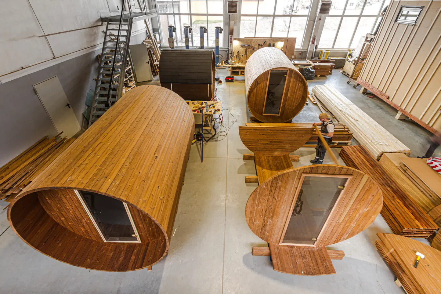 Factory workshop image showing barrel sauna components and units in production.