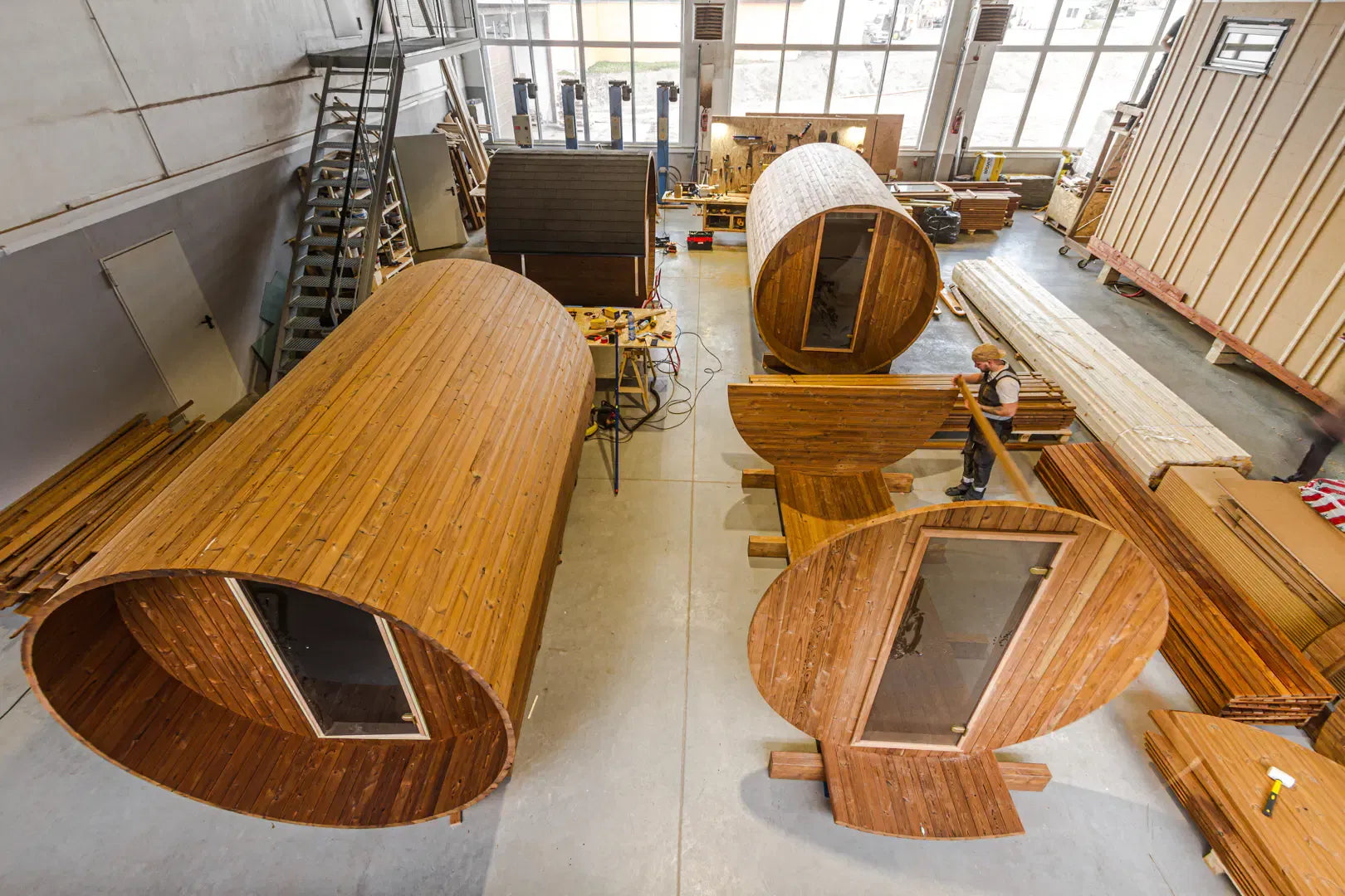 Factory workshop image showing barrel sauna components and units in production.